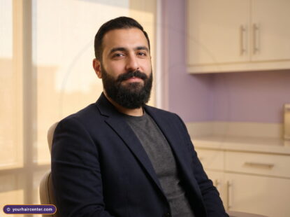 Bearded man in navy blazer relaxed in a cream and lavender clinic, the beard transplant recovery time final result